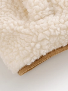 Detalle de textura de forro polar blanco y tejido marrón en chaleco de mujer