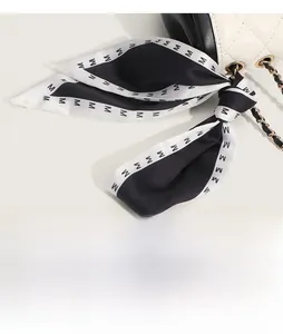 Détail d'un sac en cuir blanc matelassé avec finitions noires et foulard en soie imprimé