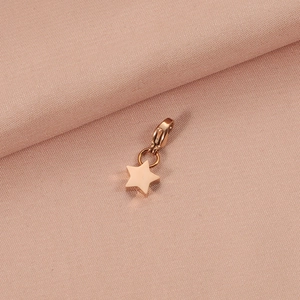 Macro shot of rose gold star pendant with lobster clasp on pink textured fabric