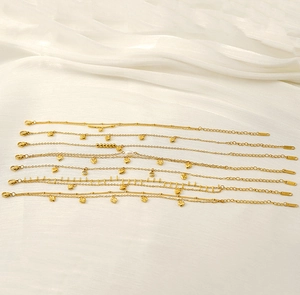 Detail of 18K gold-plated anklets with hearts and pearls on white silk background