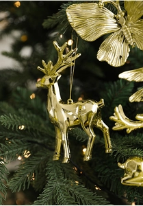 Detailed view of golden elk and butterfly ornaments hanging on a Christmas tree branch