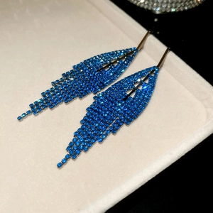 Detail view of long royal blue rhinestone fringe earrings on a velvet jewelry tray