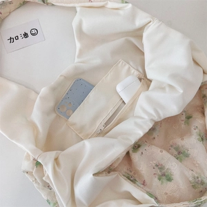 Detail of canvas bag showing interior zipper pocket with floral embroidery and storage capacity