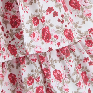 Nahaufnahme von Blumenstoff mit roten Rosen und gestuften Rüschendetails am Kleid