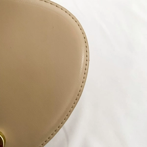 Detailed close-up of smooth beige leather texture and stitching on shell crossbody bag