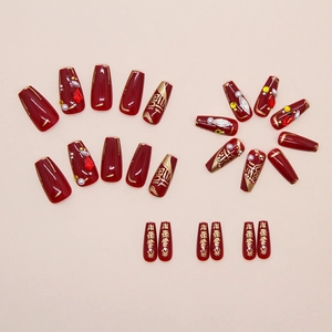Macro view of burgundy fake nails with gold calligraphy and sparkling rhinestones