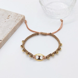 Boho layered woven bracelet with champagne cord and golden beads on white background