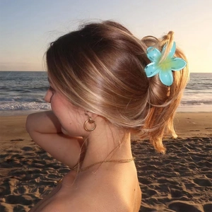 Teal gradient flower hair claw clip on blonde hair bun with beach sunset backdrop