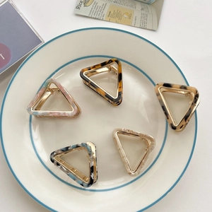 Flat lay of five acetate triangle hair claws with marble patterns and gold metal bases