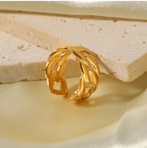 Detail of gold chain link ring on beige stone with champagne satin background