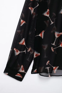 Détail d'un chemisier en mousseline noire avec imprimés de cocktails et cerises