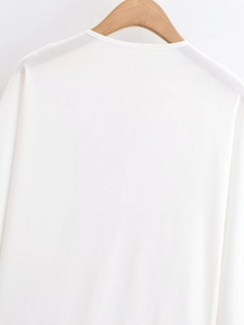 Close-up of a white crewneck batwing sleeve top on a wooden hanger with clean lighting