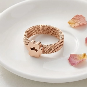 Close-up of rose gold mesh ring featuring a flower detail on a white ceramic plate