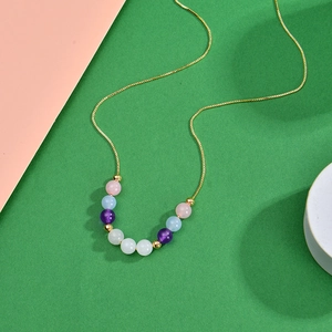 Golden necklace with multicolored quartz beads on a stylized green and pink pedestal
