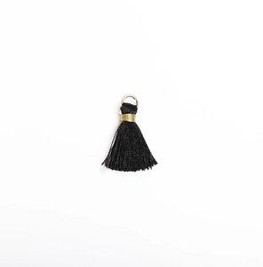 Close-up of a black mini tassel charm with a gold metal jump ring for DIY crafts