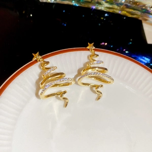 Detailed view of gold Christmas tree earrings with white zircon accents on white ceramic