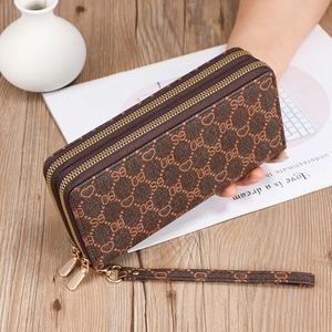 Detail of a brown double-zipper long wallet with heart pattern and wrist strap handle