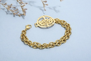 Close-up of golden double-strand bracelet with a Tree of Life pendant on blue texture