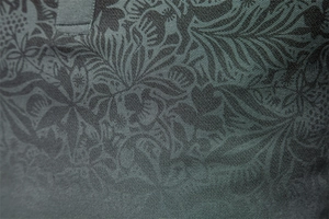 Macro detail of breathable piqué cotton fabric with tropical floral print in deep green