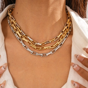 Close-up of layered gold and silver mixed link chains worn on a white shirt