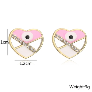 Detail view of heart-shaped evil eye earrings in gold with pink enamel and crystals