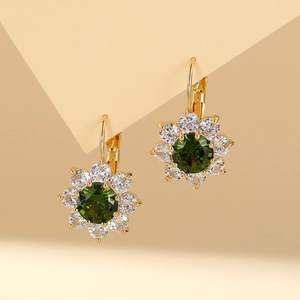 Detail of flower earrings featuring a green center stone and white diamonds in gold