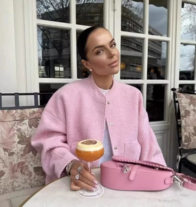 Detail of pink wool bomber jacket texture with matching heart purse in a cafe setting