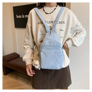 Dettaglio mini borsa da petto azzurra con trama stropicciata e ciondolo in peluche