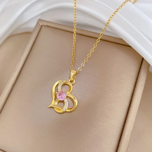 Detailed macro of gold heart pendant necklace with pink gem on elegant white silk
