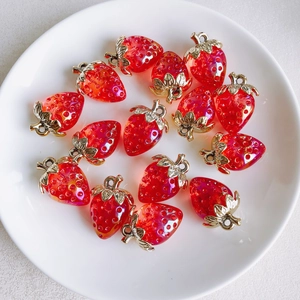 Macro view of resin strawberry charms with gold leaves and pearl inlay on a white plate