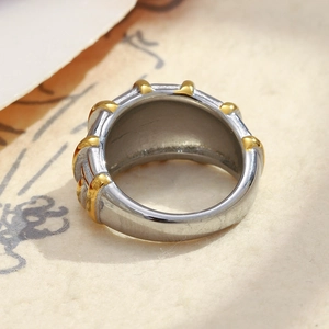 Macro view of wide two-tone industrial ring with gold studs on silver stainless steel