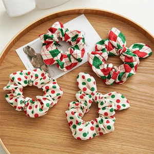 Set of four red and green plaid and polka dot fabric scrunchies with bow details on a wooden tray