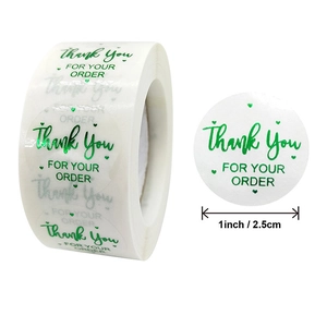 Macro detail of 1-inch white thank you sticker with gold green lettering and hearts