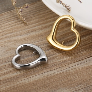 Gold and silver hollow heart-shaped pendants on a rustic wooden surface with floral decor