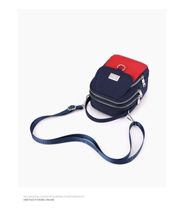 Close-up of contrast color nylon crossbody bag with multi-zipper pockets and metal logo