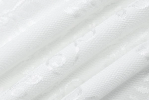 Macro shot of white lace dress fabric with delicate dotted texture and soft pleats