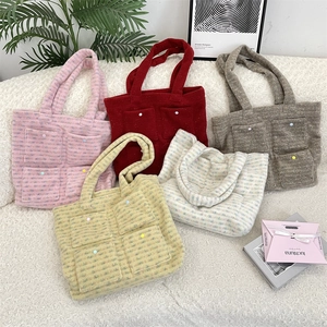 Detail shot of plush tote bags in various colors featuring decorative button pockets