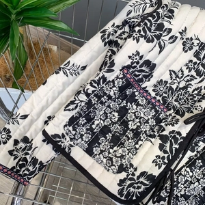 Close-up of quilted floral jacket with detailed embroidery on a black and white fabric
