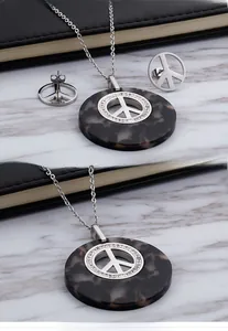 Dettaglio ravvicinato del set collana e orecchini con segno della pace in resina tartarugata