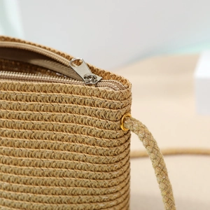 Close-up of tight straw weaving texture and golden metal zipper on the shell bag