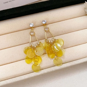 Detailed macro of golden geometric earrings with vibrant yellow layered resin disc tassels