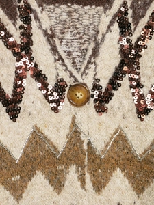 Detail of sequin and bead embroidery with button on patterned knit cardigan