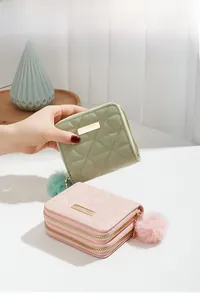 Close-up of quilted PU leather wallets in mint green and pink with fluffy pompom charms