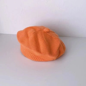 Detailed close-up showing the intricate orange knitted texture of the baby beret hat