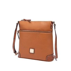 Close-up of brown pebbled leather crossbody bag showing metal plaque and stitching