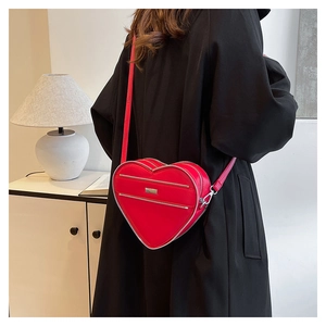 Close-up of a red heart-shaped leather crossbody bag with dual parallel metal zippers