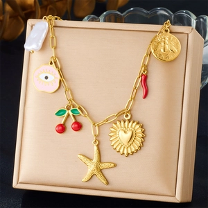 Gold chain necklace with cherry, starfish, and evil eye charms on jewelry box