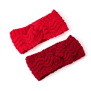 Detail of cross-knot knitted winter headbands in red and burgundy with thick wool texture