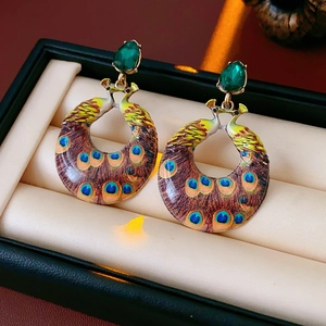 Detail of vintage peacock enamel earrings with green gemstone in a gold-tone setting