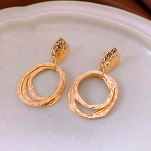 Detail of gold circular pendant earrings with hammered texture and interlocking rings
